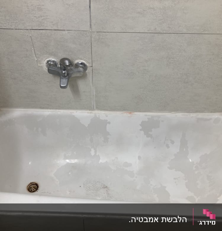 אמבטיה עם קירות מרוצפים וברז מתכת